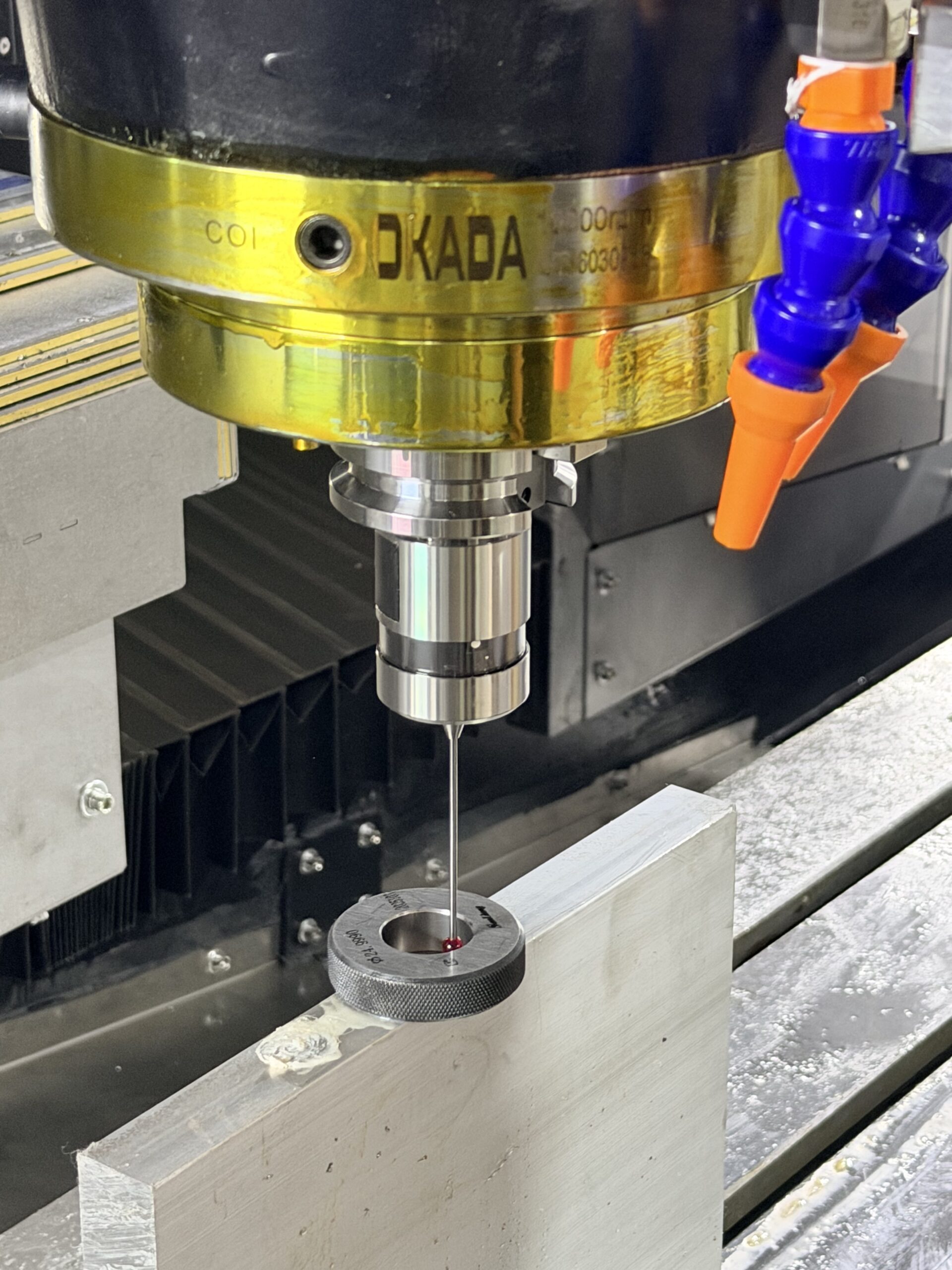 CNC spindle-mounted touch probe measuring a metal workpiece inside a machining center.